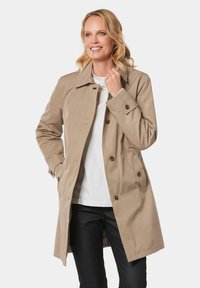 Beige trenchcoat met een dubbelbreasted ontwerp, grote knopen, een kraag en zijzakken. Gemaakt van een gladde, waterdichte stof.