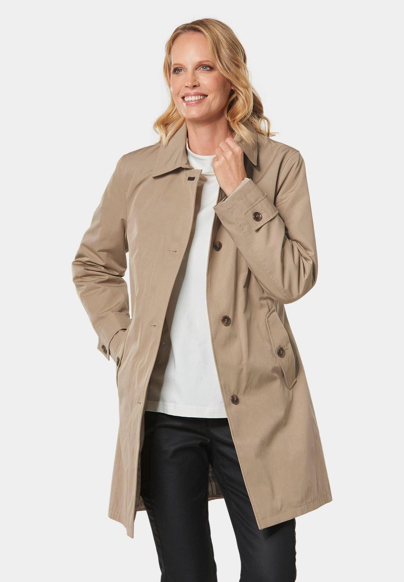Beige trenchcoat met een dubbelbreasted ontwerp, grote knopen, een kraag en zijzakken. Gemaakt van een gladde, waterdichte stof.