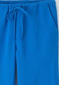 Pantalons en tissu bleu vif avec une finition texturée, taille élastique et cordon de serrage ajustable, dotés de poches latérales.