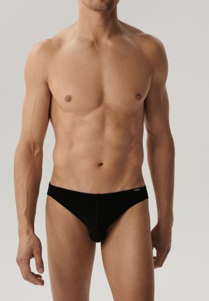 Czarne męskie majtki bikini wykonane z miękkiego materiału, z niskim stanem i metką z logo na pasku.