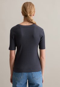 Donkerblauw geribbeld T-shirt met korte mouwen en een ronde halslijn, met een comfortabele pasvorm en een gladde textuur, gecombineerd met lichtblauwe jeans.