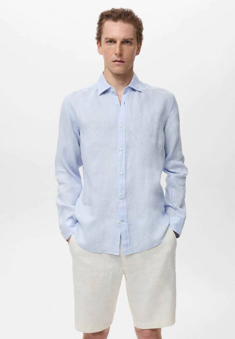 Camisa de lino de manga larga azul claro con cuello abotonado, que presenta un ajuste ligeramente relajado y una tapeta frontal limpia.