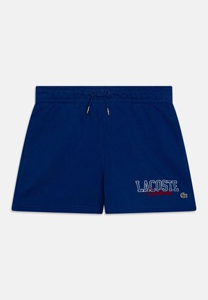 Shorts de bain bleu marine avec une taille élastique, un cordon de serrage, des poches latérales et un imprimé logo "LACOSTE" blanc/rouge sur la jambe.