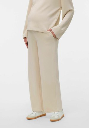 Beige oversized sweatshirt with long sleeves, paired with matching wide-leg pants. Both made from soft, stretchy fabric, featuring side pockets.
