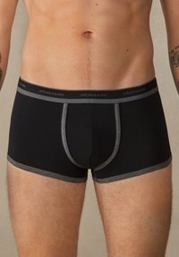 Schwarze Boxer-Briefs mit einem grauen Bund und grauen Nähten. Sie bieten eine enge Passform und eine glatte Textur, die auf Komfort und Unterstützung ausgelegt ist.