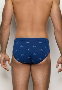 Slip in cotone blu con un motivo a ripetizione di auto di cartone animato. Il design presenta una superficie liscia e un elastico in vita confortevole.