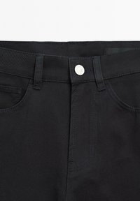 Black denim pants featuring a smooth texture, traditional five-pocket design, button closure, and contrasting stitching details.