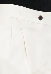 Hvide plisserede bukser med en glat tekstur, der har lukning med knap foran og elegante taljedetaljer.