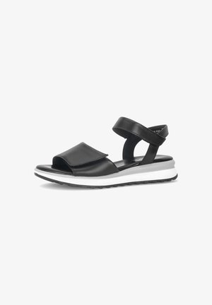 Zwarte leren sandaal met brede voorriem en enkelriem, witte gevoerde zool en getextureerde zwarte buitenzool, zijaanzicht op witte achtergrond.