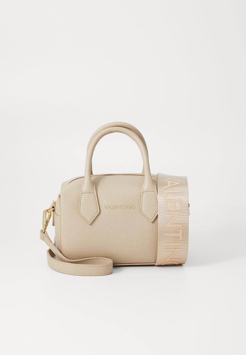 Beige leather handbag with two top handles, adjustable strap, and embossed logo. Features a textured surface and flat shape.