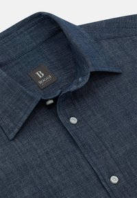 Camicia button-up blu scuro realizzata in un tessuto testurizzato, con colletto alla francese e un'etichetta del marchio all'interno del colletto.