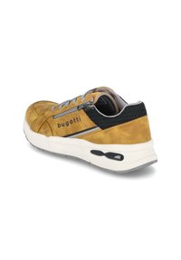 Geel suède sneaker met grijze accenten, voorzien van een geperforeerd ontwerp, zwarte textielkraag en witte tussenzool met een zwart detail.