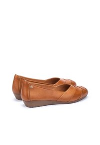 Bailarinas de cuero color marrón claro con punta redondeada, un sutil diseño entrelazado, tacón bajo y una textura suave con costuras decorativas.