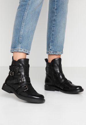 Bottines en cuir noir avec plusieurs sangles et boucles, bout rond et fermeture éclair sur le côté ; semelle plate avec un léger talon.