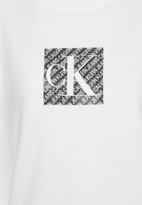 Valkoinen huppari, jossa on musta suorakulmainen logo, jossa toistuu teksti "CALVIN KLEIN JEANS" ja keskiössä on merkittävä "CK".