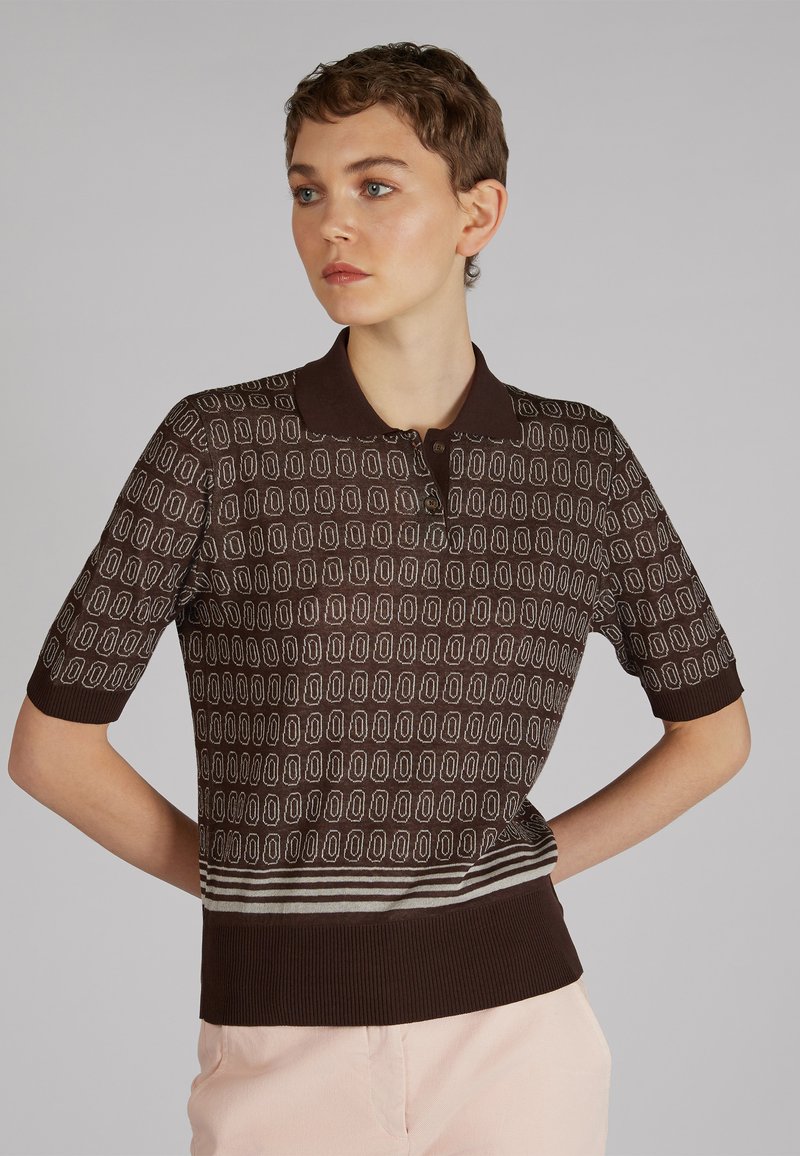 Polo marrón de manga corta con textura estampada que presenta formas ovaladas y un dobladillo y cuello de canalé en contraste. Tejido de punto ligero.