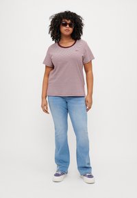 Red and white striped t-shirt with a round neckline, paired with light blue flared jeans and white sneakers with purple accents.
