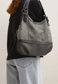 Torba typu hobo z teksturowaną szaro-skalną skórzaną podstawą, miękką oliwkowozieloną górą, metalowymi akcentami oraz regulowanym paskiem.