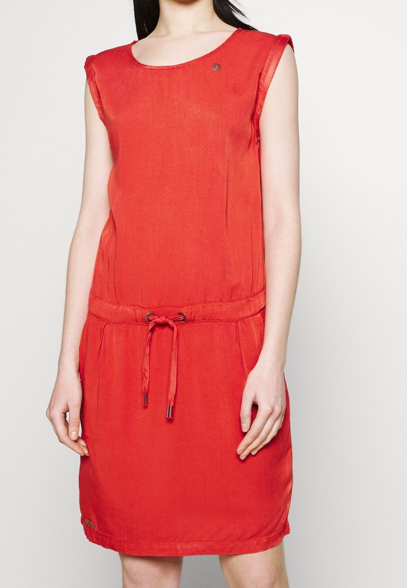 Vestido rojo sin mangas hecho de una tela liviana con escote redondo, cintura ajustable con cordón y acentos de metal plateado.