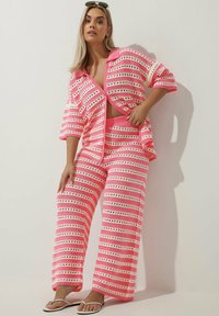 Completo a righe in rosa e bianco, composto da un cardigan morbido e ampio e pantaloni a gamba larga coordinati, realizzato in un tessuto morbido e testurizzato.