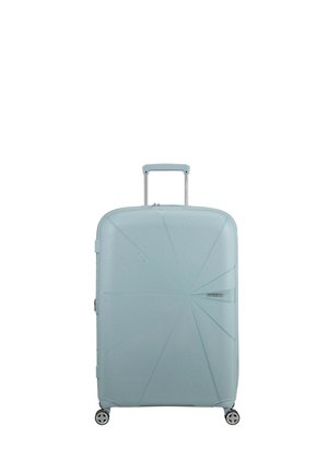 Hard-shell suitcase in light blue, featuring a textured, angular design with recessed lines, 4 wheels, and a retractable handle.