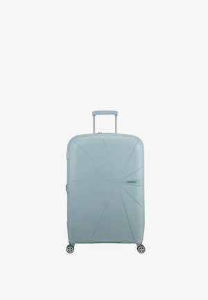 Valigia rigida di colore azzurro chiaro, con un design angolare e testurizzato, linee incassate, 4 ruote e un manico estraibile.