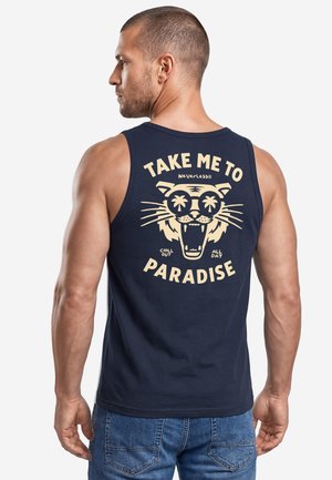 Man wearing navy tank top with beige graphic of a roaring tiger wearing sunglasses and the text "Take me to paradise" on the back.