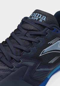 Αθλητικό παπούτσι σε ναυτικό μπλε με σκούρα κορδόνια, διαπνέον άνω μέρος από δίχτυ, λογότυπο σε ανοιχτό μπλε και κείμενο "Σύστημα Αερισμού" στη πλευρά.