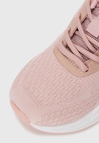 Scarpa sportiva rosa chiaro con upper in rete testurizzata, punta rinforzata e suola bianca flessibile con un sottile accento rosa.