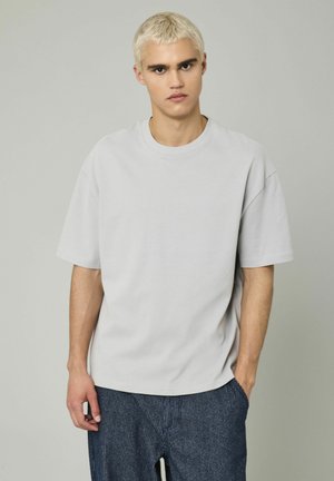 T-shirt gris clair à manches courtes, en coton, avec une coupe décontractée, un col rond, et sans motifs ni accents visibles.