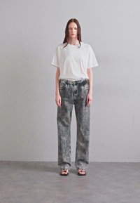 White cropped t-shirt paired with high-waisted, loosely fitting gray denim jeans featuring a marbled texture and subtle fading details.