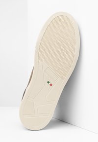Sneaker marrone chiaro con suola in gomma testurizzata e intersuola color crema. Presenta un marchio in rilievo e dettagli sulla taglia sulla suola.