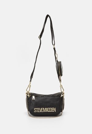 Bolso bandolera negro de Steve Madden con cadena dorada, correa ajustable y pequeño estuche desmontable sobre un fondo claro.