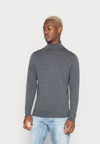 Grå turtleneck sweater lavet af strikket stof, med en tætsiddende pasform og lange ærmer, parret med lyseblå jeans.