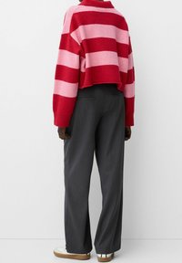 Red and pink striped cropped sweater paired with gray wide-leg trousers and white sneakers. Soft knit texture; casual design.