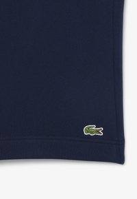 T-shirt in cotone blu navy con finitura testurizzata, caratterizzato da un piccolo logo di coccodrillo verde ricamato vicino all'orlo.