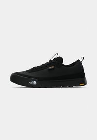 Black athletic shoes made of synthetic material, featuring laces, a cushioned sole, and a textured rubber outsole with "Vibram" branding.