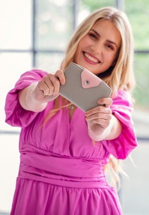 Gray wallet made of leather with a pink flap closure and silver button detail. Features soft texture and a rectangular shape.