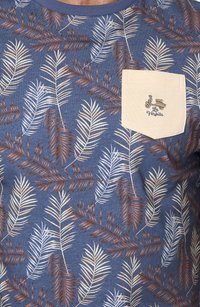 Camisa de manga corta en azul con bolsillo beige. Presenta un estampado de plantas con hojas en tonos blancos y marrones. El bolsillo tiene un logo de scooter bordado.