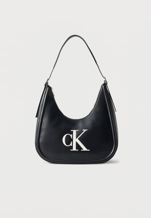 Black crescent-shaped shoulder bag with white "cK" logo on front and a single strap, against a plain light background.