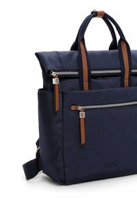 Tumedast sinine seljakott pruunide nahkdetailidega, tõmblukkudega taskud ja kaks ülemist sangapära. Iseloomustab struktureeritud disain ja reguleeritav rihm.