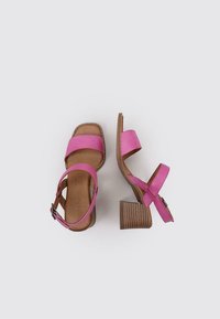 Sandales à talons roses avec deux larges brides sur les orteils, une bride de cheville ajustable et un talon carré en cuir texturé marron. Dessus en cuir.