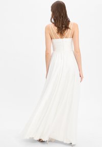 Witte maxi-jurk met een getailleerde bodice en een vloeiende rok, met dunne banden, een cinched taille en een rits aan de achterkant.