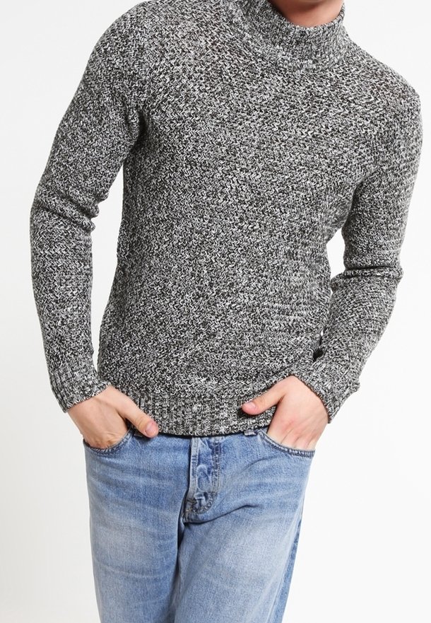 Grijze en zwarte gemarmerde gebreide turtleneck trui met lange mouwen en ribgebreide manchetten, gecombineerd met blauwe denim jeans. De textuur lijkt zacht te zijn.