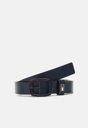 Ceinture en cuir bleu marine avec boucle ovale noire et plaque métallique rectangulaire affichant le logo "Tommy Jeans", présentée sur un fond blanc.