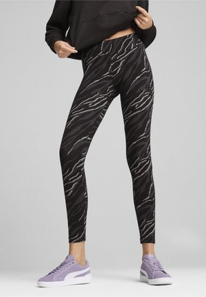 Sorte og grå tigerstribede leggings med høj talje, lavet af glat stof. Sammen med lyse lilla sneakers.