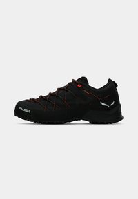 Czarne niskie buty trekkingowe z pomarańczowymi sznurówkami, teksturowaną podeszwą z przyczepnością oraz odblaskowymi logo na palcach i z tyłu.