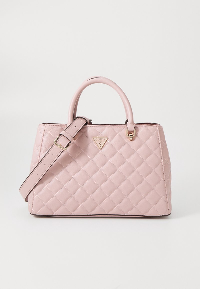 Sac à main matelassé rose clair avec double poignée, bandoulière réglable et logo triangulaire doré Guess au centre devant.