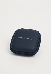Tumes kõva kest tumesinises värvitoonis, millel on sile matt viimistlus, varustatud tõmblukuga ja "TOMMY HILFIGER" logo valgete, punaste ja siniste aktsentidega.