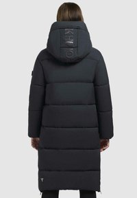 Lang, puffet sort parka med hætte. Har horisontalt kviltede sektioner, logo-detalje på hætten, sidelommer og en lynlås i kanten.